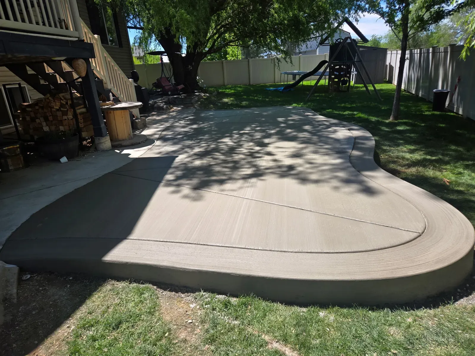 Curved broom-finish patio with integrated concrete curbing in a Perry backyard