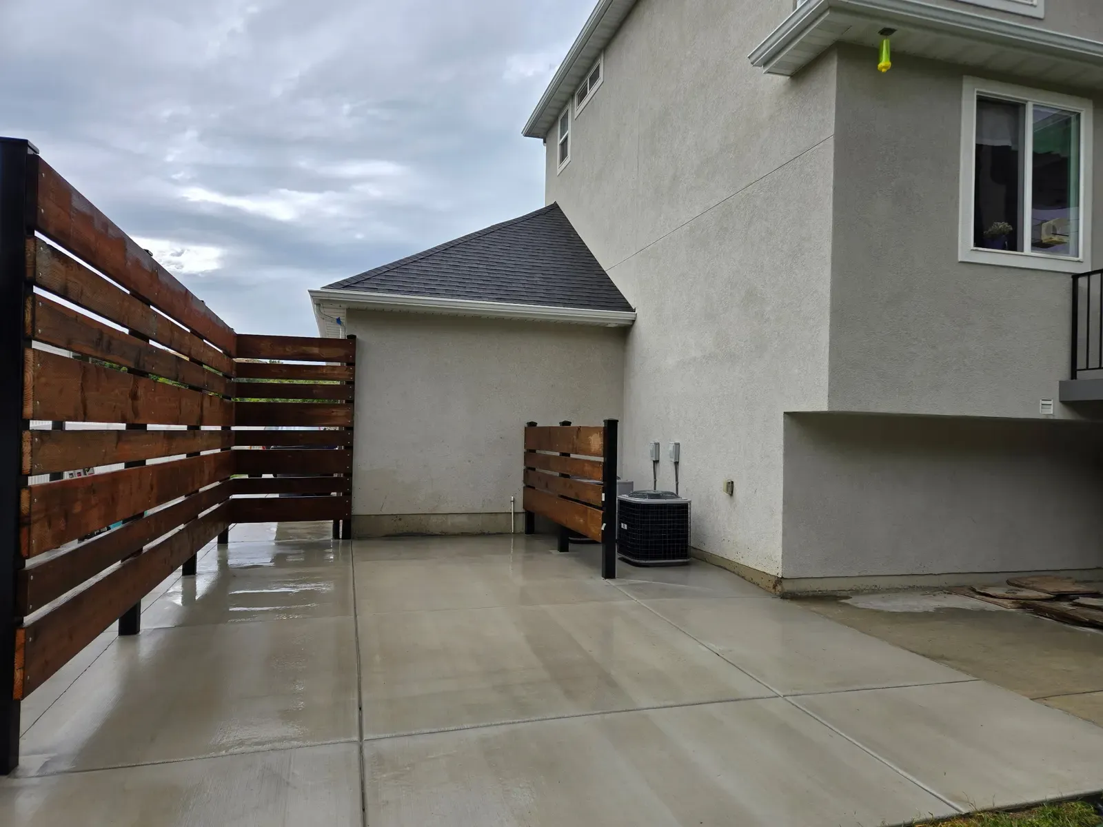 Completed concrete patio with a horizontal wood privacy fence in South Weber