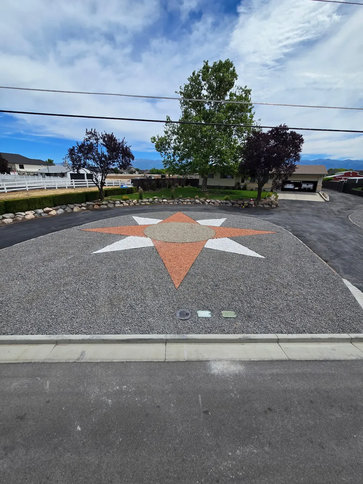Decorative gravel star in a Syracuse driveway, framed by concrete curbing