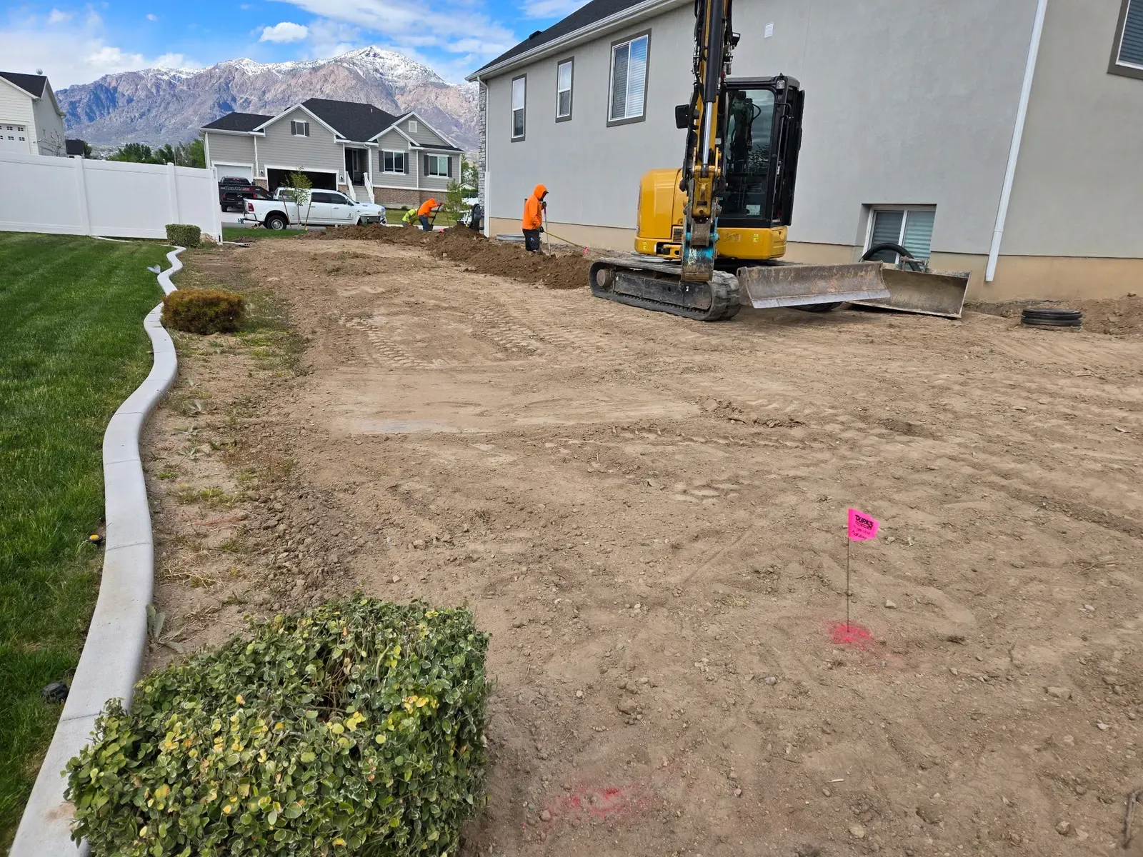 Landscape curbing, lawn, and excavator in a Harrisville yard near Ogden
