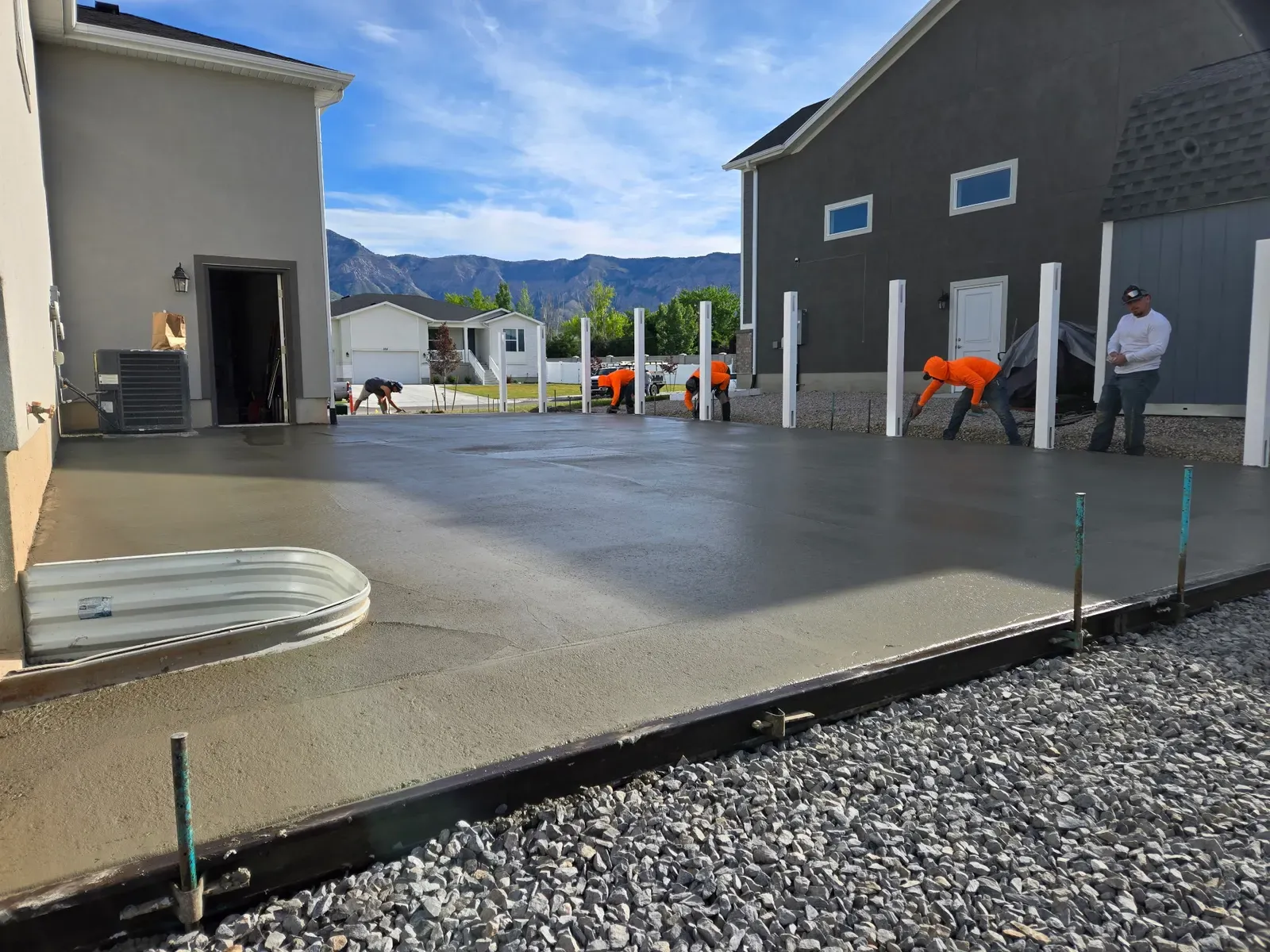 Crew troweling a fresh concrete slab between homes in Harrisville