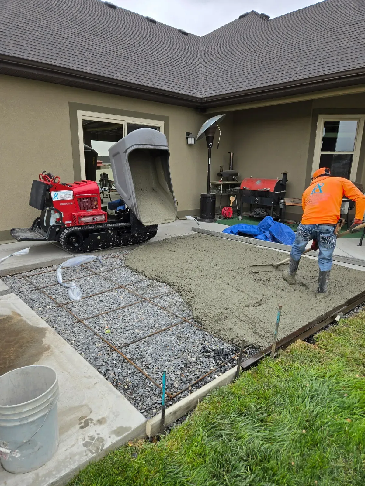 Crew spreading fresh concrete from a tracked dumper onto a Hooper patio