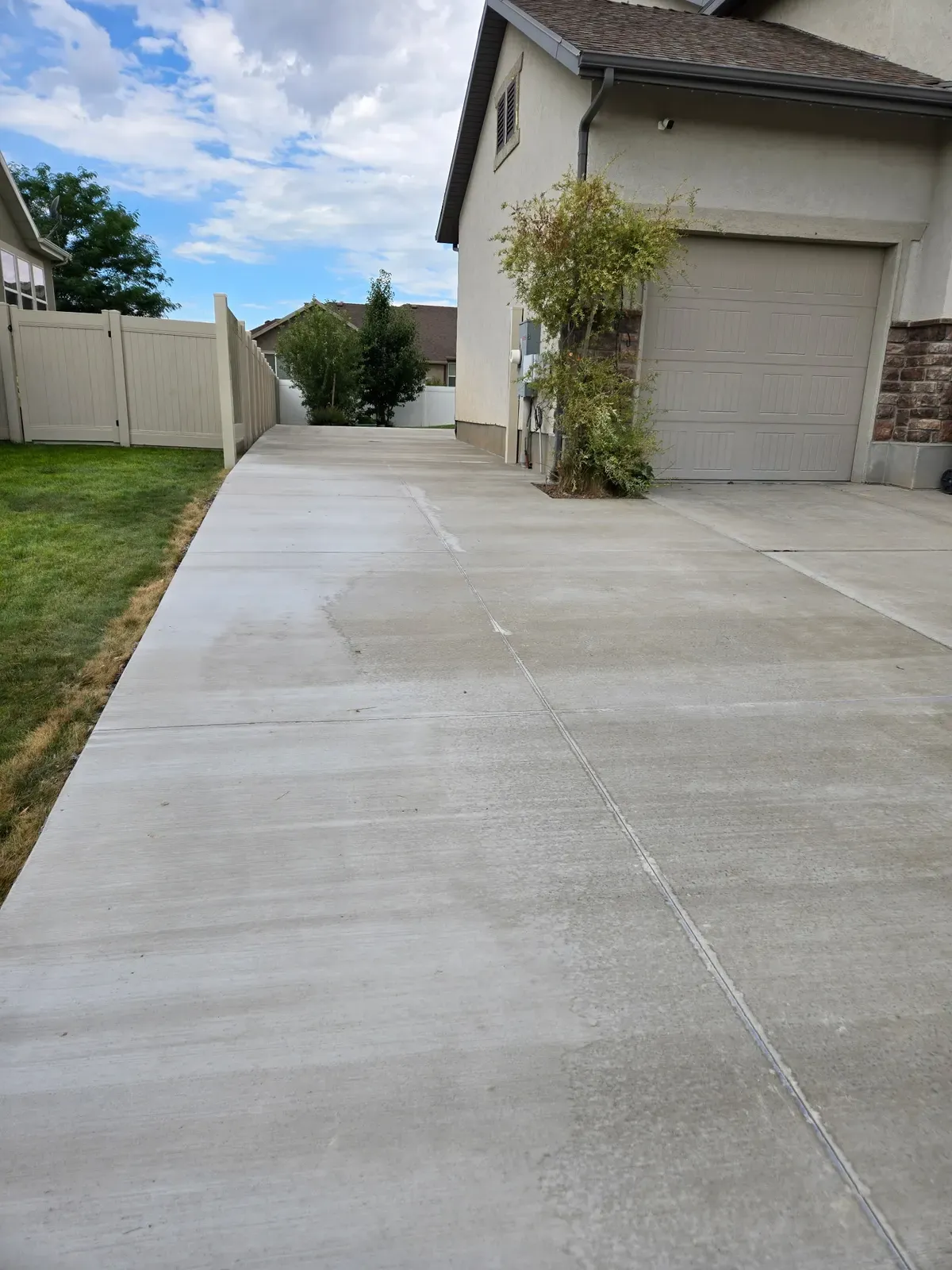 New broom-finish concrete driveway and side walkway beside a Roy home