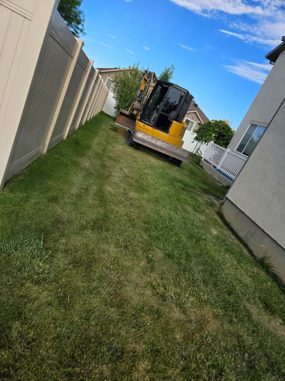 Mini excavator staged in a Roy side yard before walkway excavation